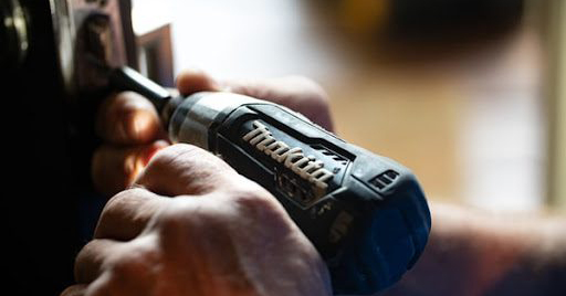 Electric cordless drill screwing into home appliance